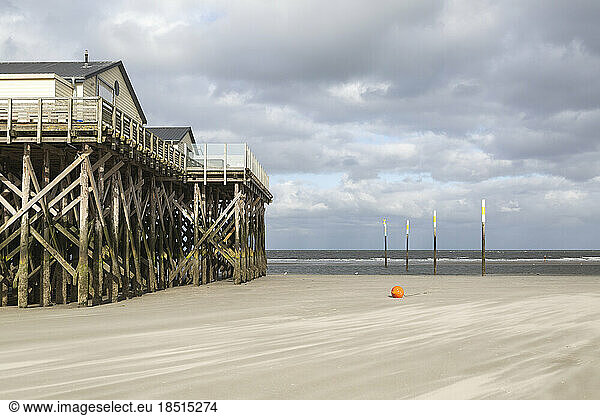 Germany  Schleswig-Holstein  St. Peter-Ording  Cloudy sky over stilt houses on sandy beach