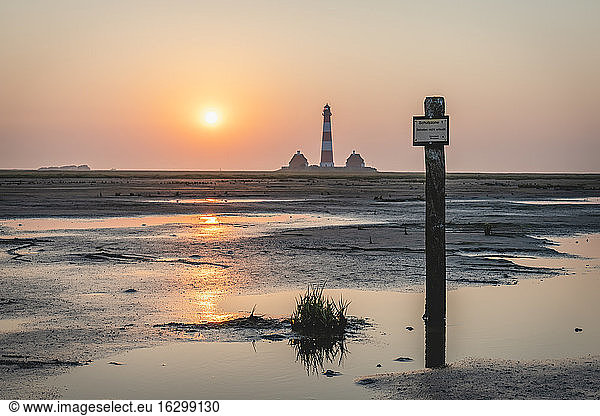 Germany  Schleswig-Holstein  Westerhever  Coastal signpost at sunrise with Westerheversand Lighthouse in background