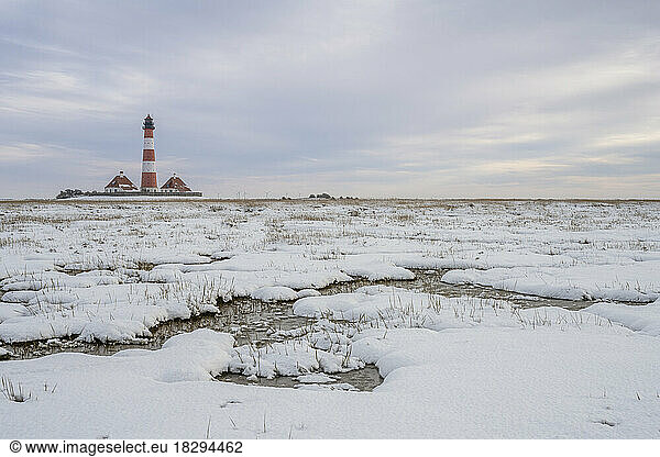 Germany  Schleswig-Holstein  Westerhever  Snow-covered landscape at dusk with Westerheversand Lighthouse in background