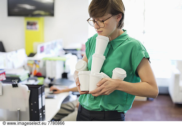Geschäftsfrau beim Balancieren von leeren Kaffeetassen