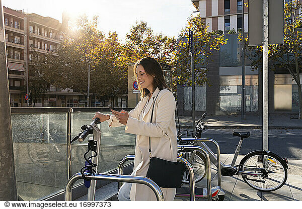 Geschäftsfrau beim kontaktlosen Bezahlen an einer Fahrradparkstation in der Stadt