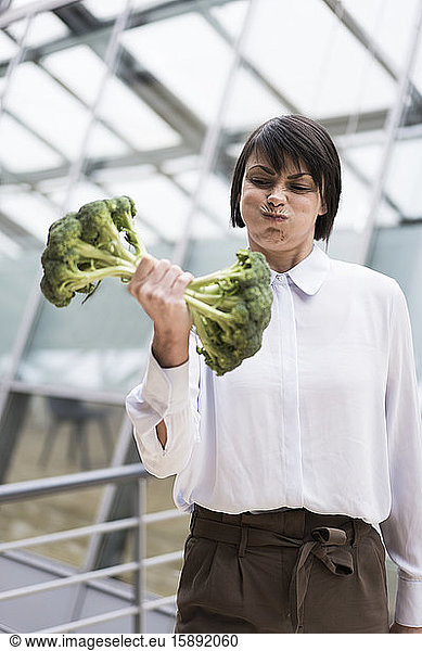 Geschäftsfrau beim Krafttraining mit Brokkoli