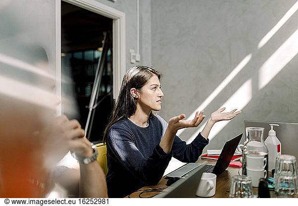Geschäftsfrau beim Sitzen am Arbeitsplatz gestikulierend