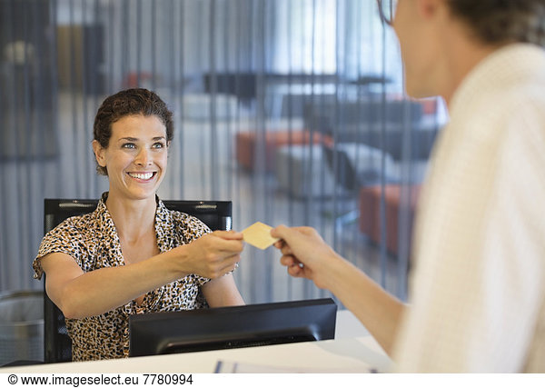 Geschäftsfrau übergibt Kreditkarte an Mitarbeiterin