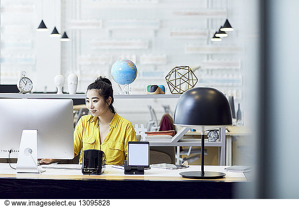 Geschäftsfrau  die am Desktop-Computer arbeitet  während sie im Kreativbüro am Schreibtisch sitzt