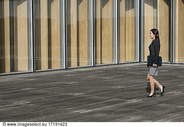 Geschäftsfrau geht an einem modernen Gebäude in Paris vorbei