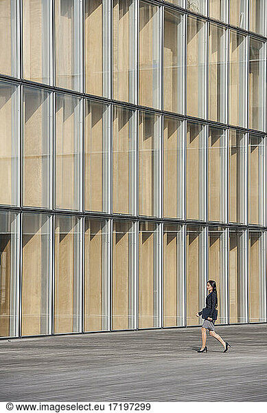 Geschäftsfrau geht an einem modernen Gebäude in Paris vorbei