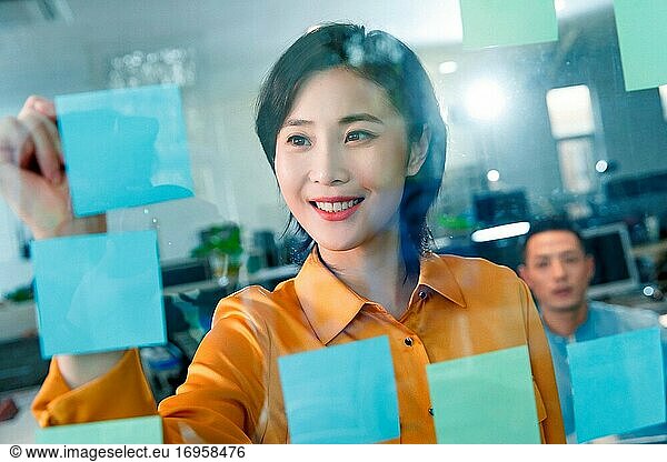 Geschäftsfrau im Büro zum Schreiben auf Post-it-Zettel