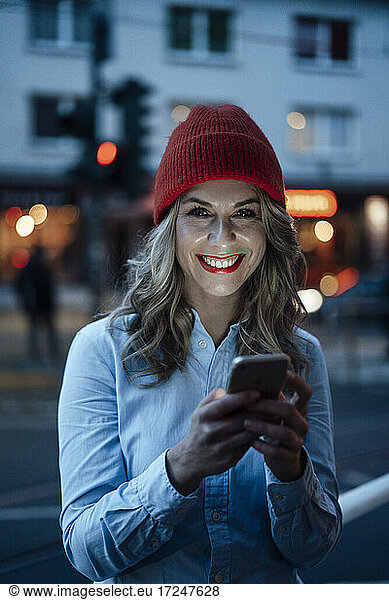 Geschäftsfrau lächelnd bei der Verwendung eines Smartphones bei Sonnenuntergang