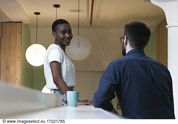 Geschäftsfrau lächelt beim Anblick eines Kollegen in der Cafeteria