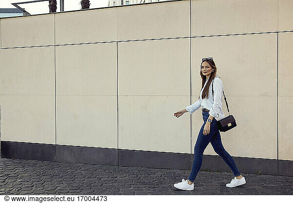 Geschäftsfrau mit Handtasche  die auf dem Gehweg gegen eine Mauer läuft