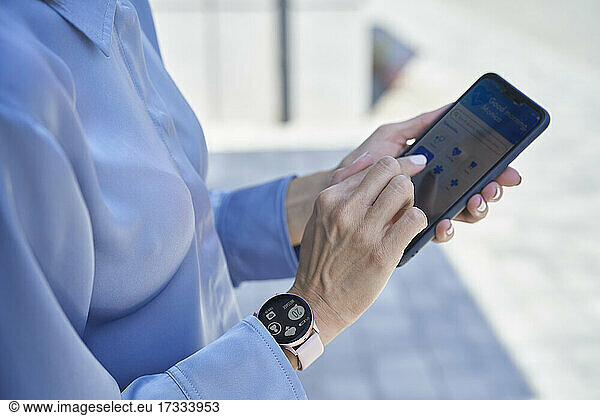 Geschäftsfrau mit intelligenter Armbanduhr und Mobiltelefon