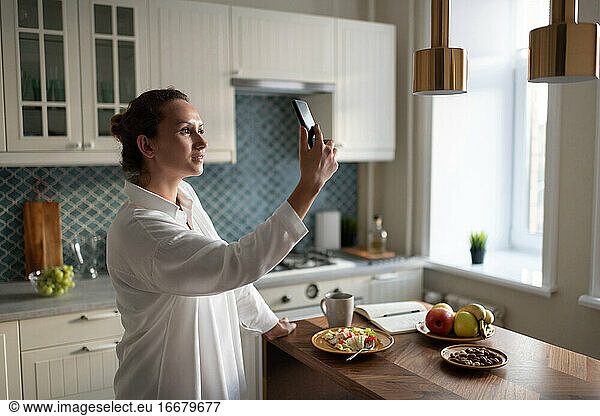 Geschäftsfrau nutzt Smartphone zur Kommunikation in der Küche