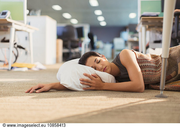 Geschäftsfrau schläft mit Kissen im Bürogeschoss
