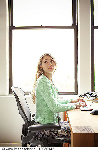 Geschäftsfrau sitzt am Büroschreibtisch am Fenster