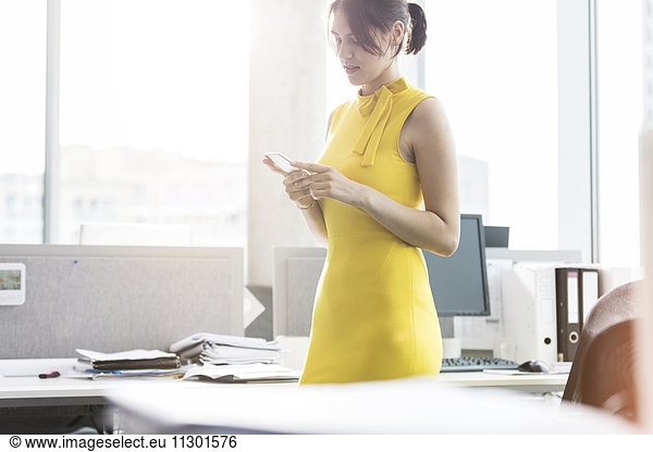 Geschäftsfrau SMS mit Handy im Büro