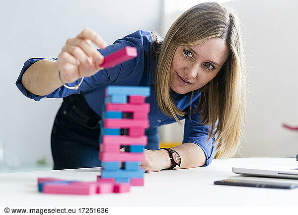 Geschäftsfrau spielt im Büro ein Spiel zum Entfernen von Blöcken