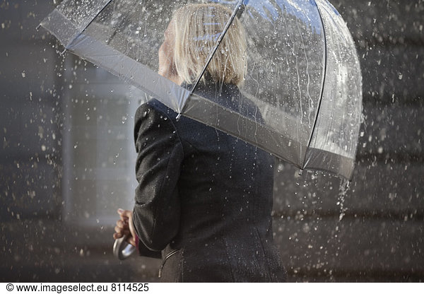 Geschäftsfrau unter Schirm im Regen