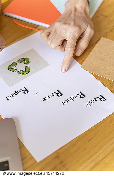 Geschäftsfrau zeigt auf Papier mit Recycling-Symbol im Büro