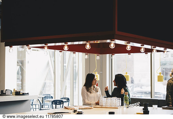 Geschäftsfrauen diskutieren bei Tisch im hell erleuchteten Büro
