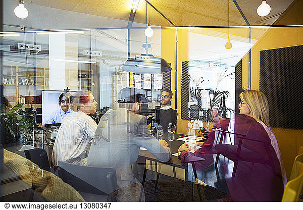 Geschäftsleute bei Videokonferenzen bei Besprechungen im Büro durch Glasfenster gesehen