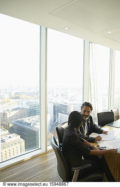 Geschäftsleute besprechen Papierkram in hochgelegenem Konferenzraum