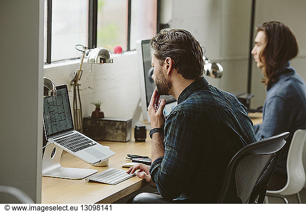 Geschäftsleute  die an Desktop-Computern bei Tisch im Büro arbeiten