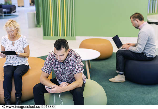 Geschäftsleute  die Technologien in der Lobby im modernen Büro nutzen