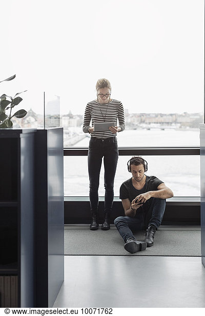 Geschäftsleute  die Technologien per Fenster im Büro nutzen