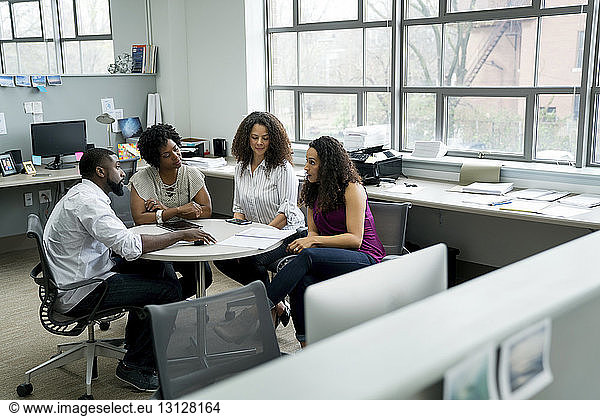 Geschäftsleute diskutieren  während sie im Büro am Tisch sitzen