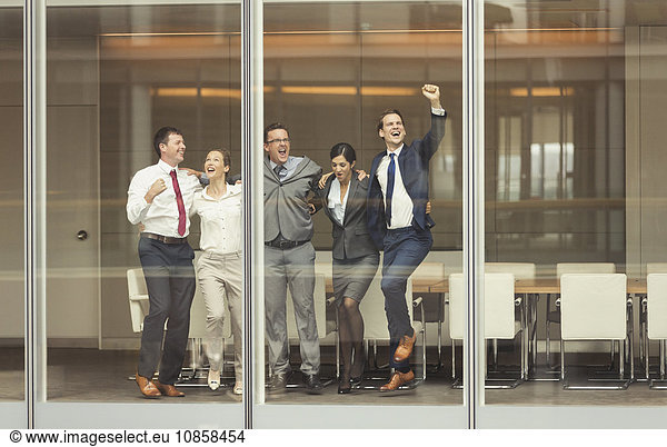 Geschäftsleute feiern und jubeln am Konferenzraumfenster