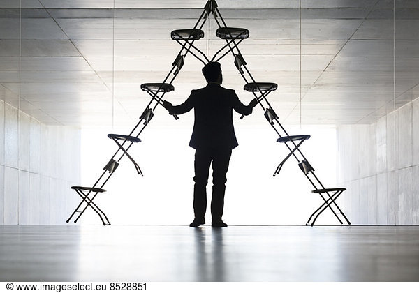 Geschäftsmann arrangiert Bürostuhl-Installationskunst