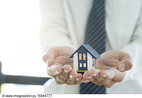 Geschäftsmann Hand halten das Haus Modell retten kleines Haus. Haus