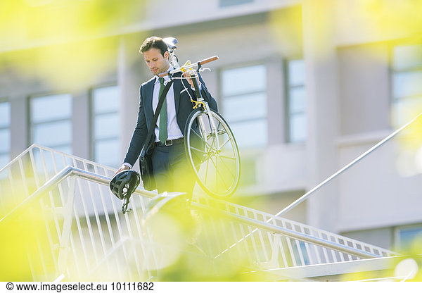 Geschäftsmann im Anzug mit Fahrrad in der Stadt