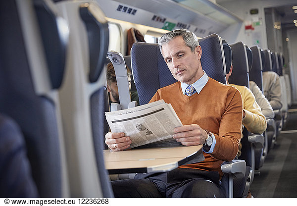 Geschäftsmann liest Zeitung im Personenzug