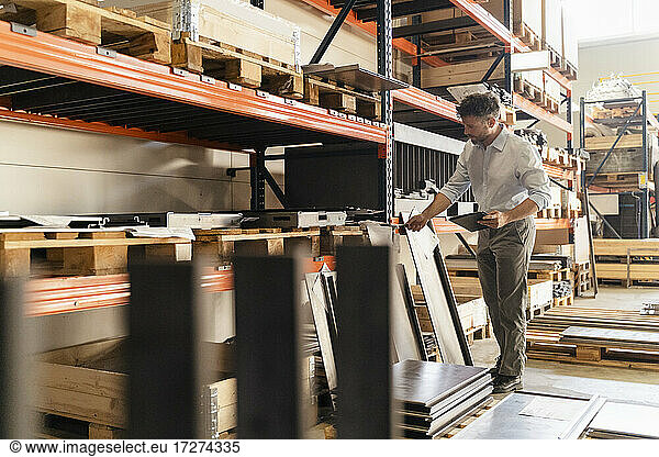 Geschäftsmann mit digitalem Tablet  der in einer Fabrik stehend Material inspiziert