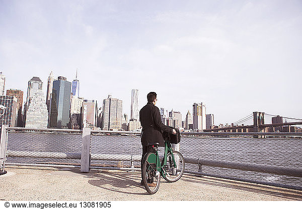 Geschäftsmann mit Fahrrad  der vom Aussichtspunkt aus die Stadt genießt