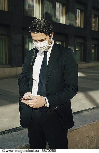 Geschäftsmann mit Gesichtsmaske mit Smartphone