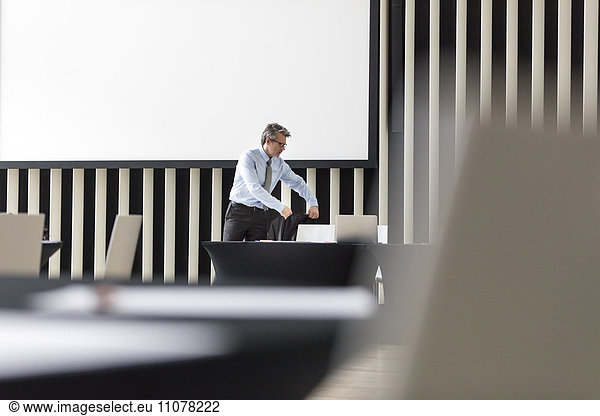 Geschäftsmann platziert Jacke auf Stuhl im Konferenzraum