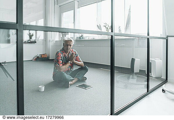 Geschäftsmann sitzt im Gebet Position auf dem Boden im Büro