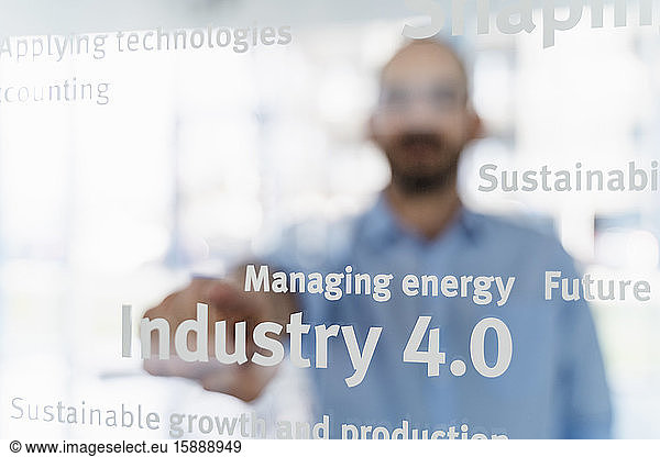 Geschäftsmann vor Glasscheibe auf Worte deutend  Industrie 4.0