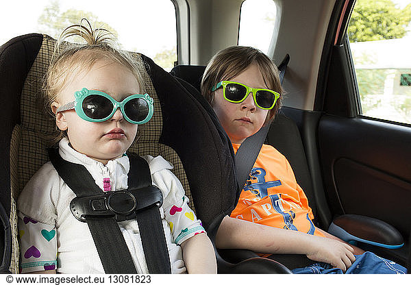 Geschwister mit Sonnenbrille im Auto unterwegs