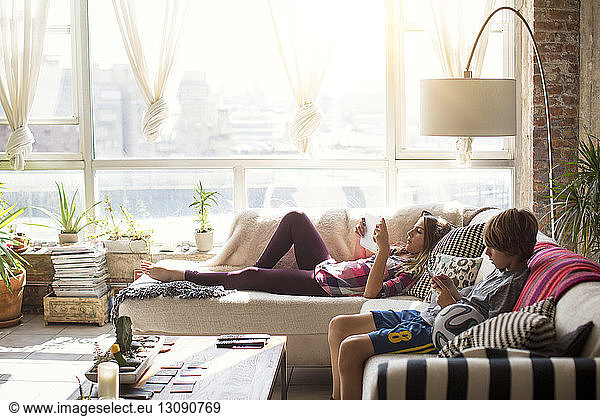 Geschwister nutzen Technologien beim Entspannen im Wohnzimmer