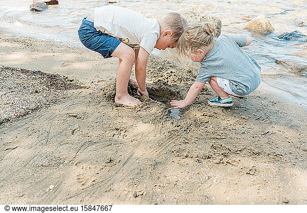 Geschwister spielen gemeinsam am Strand.