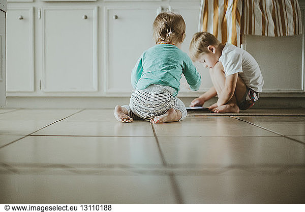 Geschwister spielen zu Hause auf dem Fliesenboden