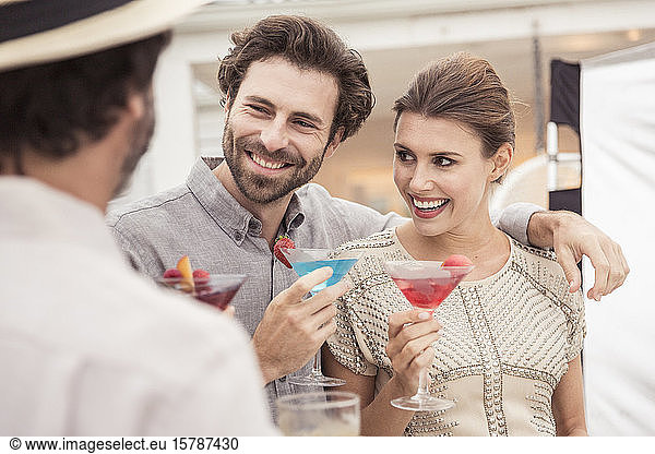Geselliges Beisammensein von Paar und Freund auf einer Cocktailparty