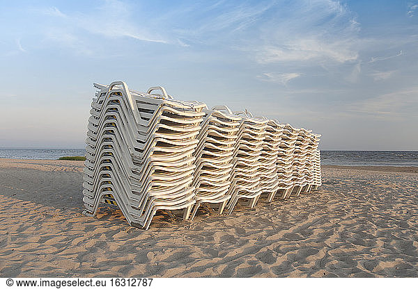 Gestapelte Liegestühle an einem Strand
