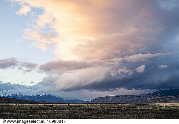 Gewitterwolken über Bergen und Ebenen mit lebhaften Farben bei Sonnenuntergang