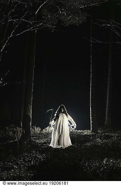 Ghost with scythe walking in forest at night
