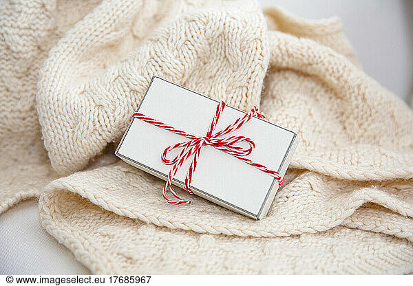 Gift box wrapped with red and white string on woolen blanket